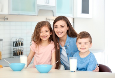 Photo of Happy family having breakfast with milk in kitchen