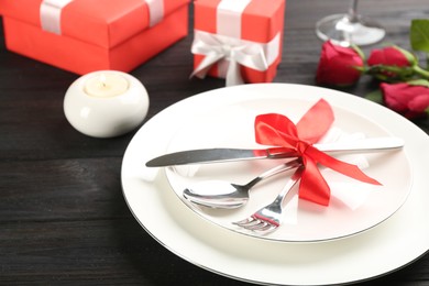 Photo of Beautiful table setting for Valentine's Day dinner on black wooden background, closeup