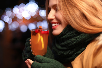 Photo of Happy woman with tasty mulled wine at winter fair