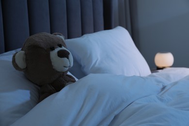 Photo of Cute toy bear in bed at home