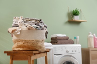 Photo of Laundry basket with baby clothes and toy on table in bathroom. Space for text