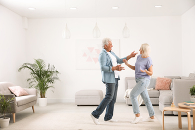 Happy mature couple dancing together in living room