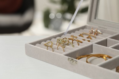 Jewelry box with different golden accessories on white wooden table indoors, closeup