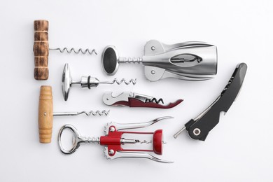 Different corkscrews on white background, flat lay