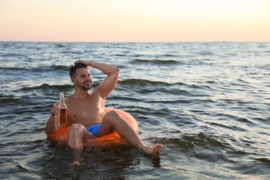 Photo of Happy young man on inflatable ring in water