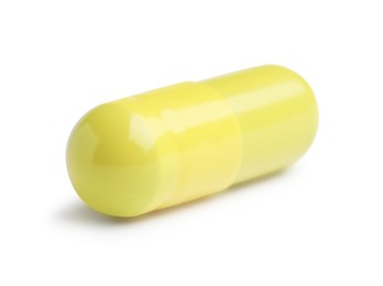 One yellow pill isolated on white. Medicinal treatment