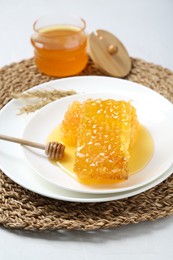 Photo of Natural honeycombs with tasty honey and dipper on white table