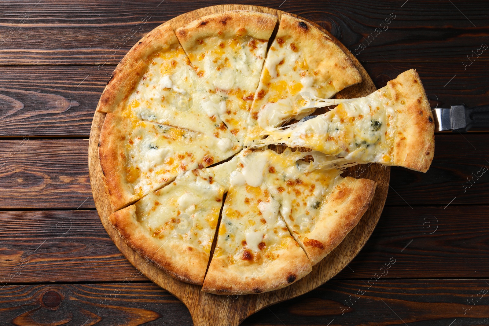 Photo of Taking piece of delicious cheese pizza at wooden table, top view