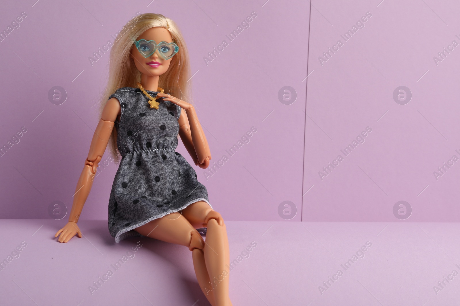 Photo of Mykolaiv, Ukraine - September 4, 2023: Beautiful Barbie with stylish eyeglasses doll sitting on lilac background, space for text