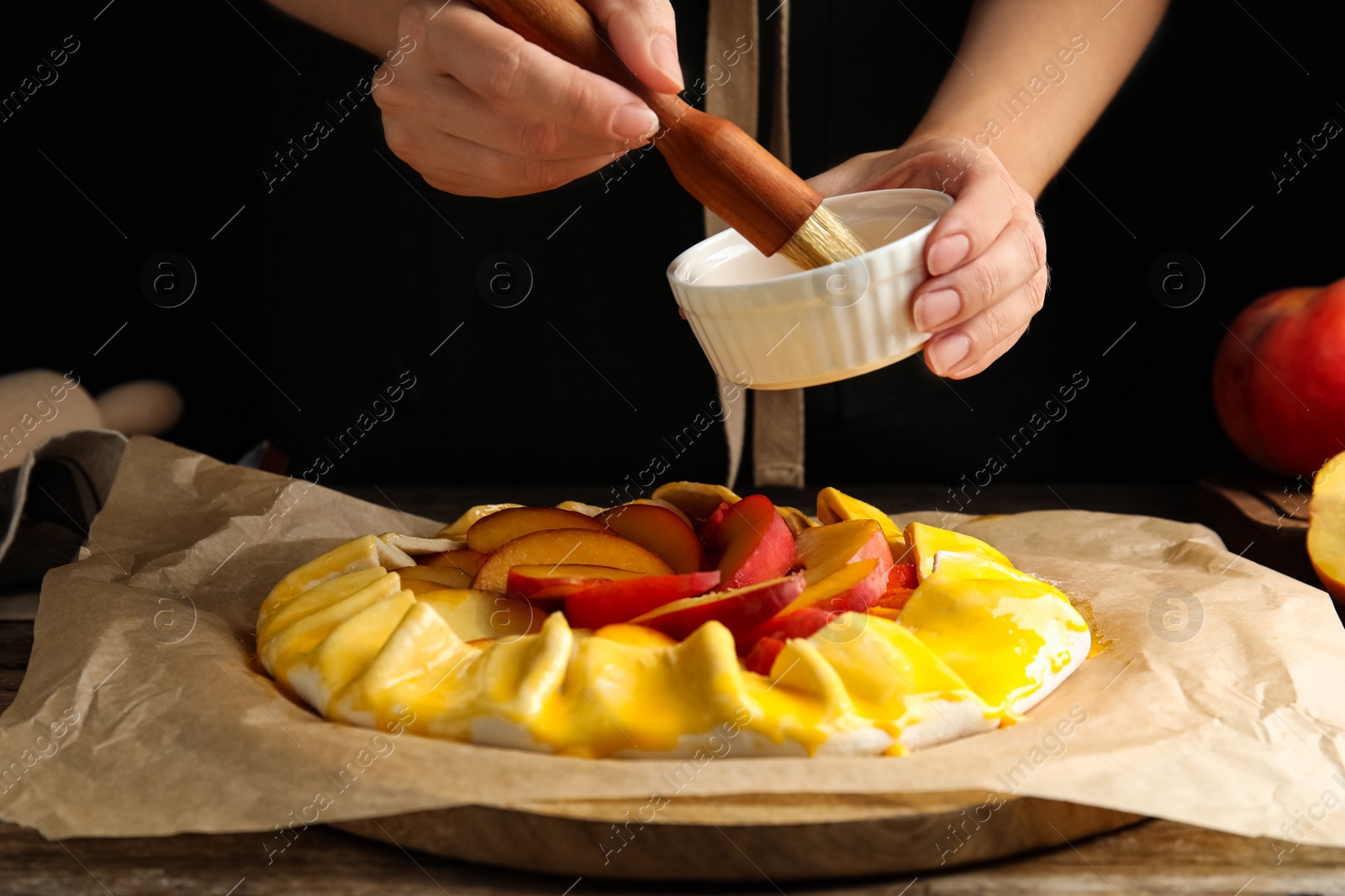 Photo of Woman making peach pie at wooden table, closeup