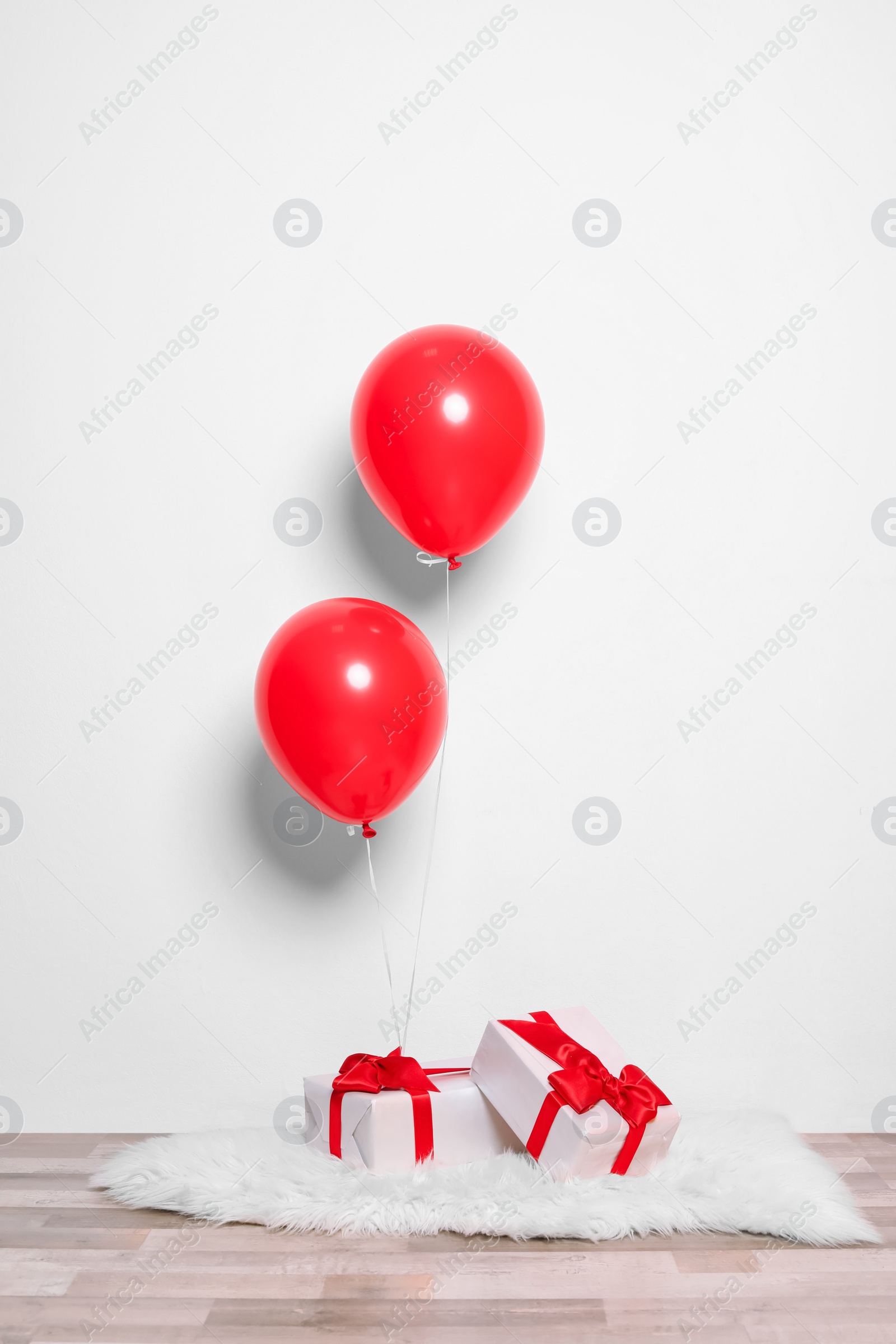 Photo of Red balloons and gifts on floor against white wall