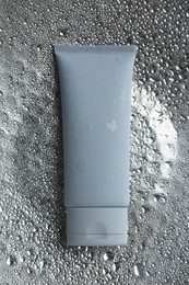 Moisturizing cream in tube on silver background with water drops, top view