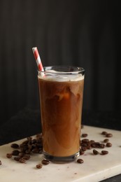 Photo of Refreshing iced coffee with milk in glass and beans on table against dark gray background