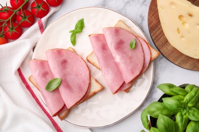 Photo of Delicious sandwiches with ham and products on white table, flat lay