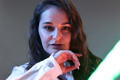 Portrait of beautiful young woman on color background with neon lights