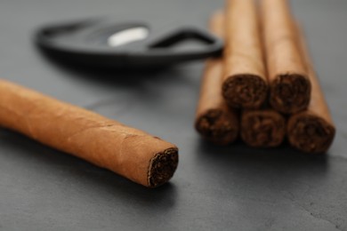 Photo of Cigars wrapped in tobacco leaves on black table, closeup