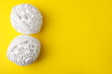 Photo of Laundry dryer balls on yellow background, flat lay. Space for text