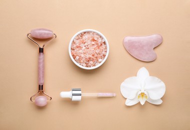 Photo of Flat lay composition with gua sha stone and face roller on beige background