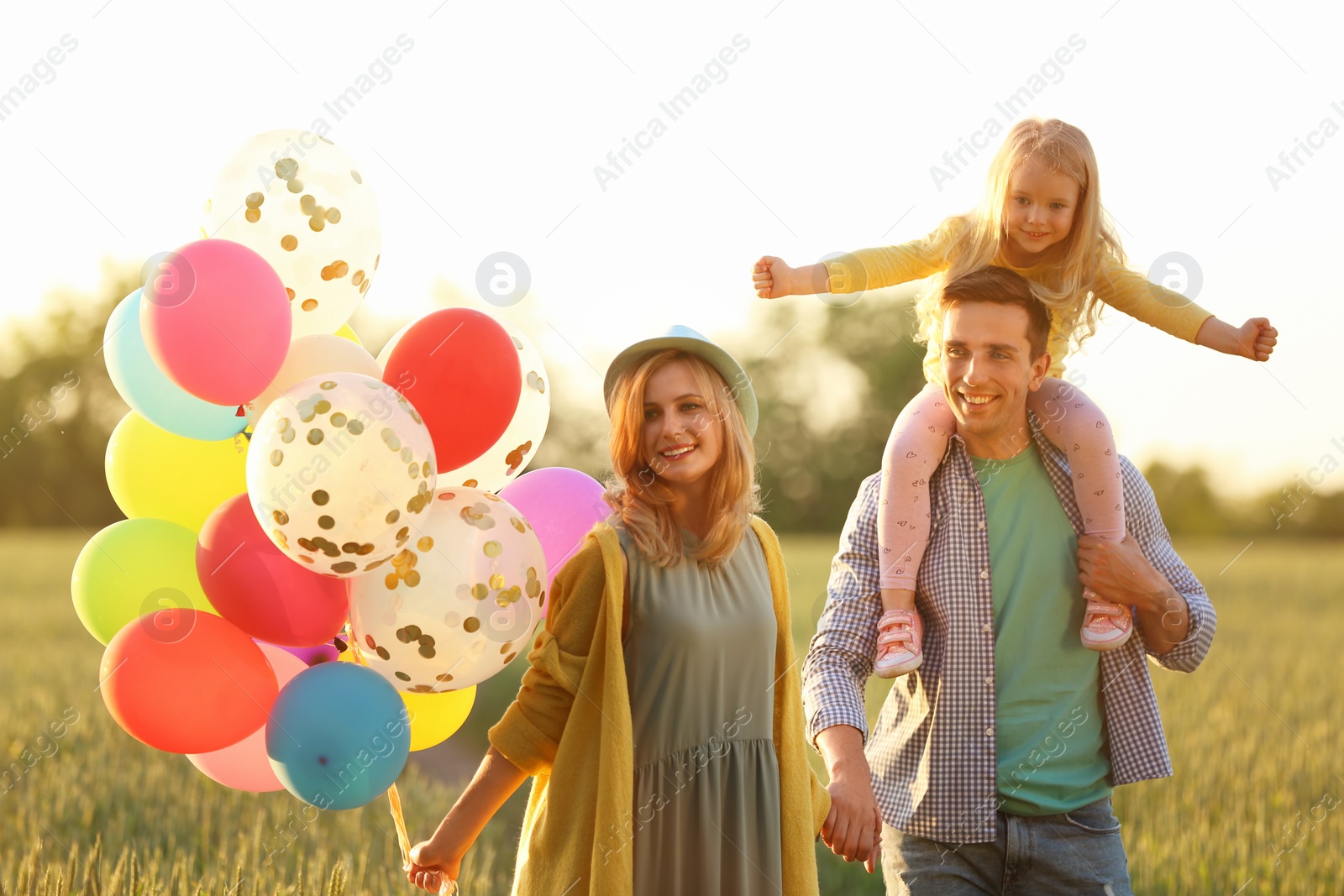 Photo of Happy family with colorful balloons in field on sunny day