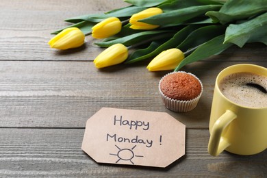 Happy Monday message, aromatic coffee, cupcake and tulips on wooden table