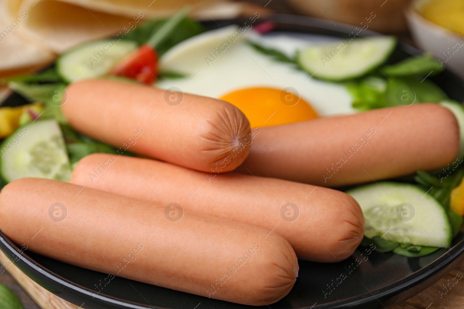 Photo of Delicious breakfast with boiled sausages and fried egg on wooden table, closeup