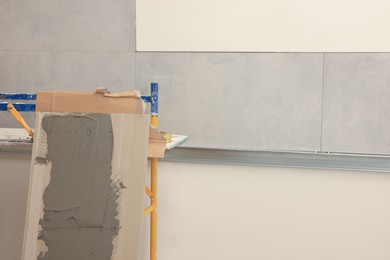 Photo of Tile with adhesive mix near wall indoors, space for text