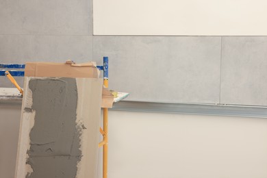 Tile with adhesive mix near wall indoors, space for text