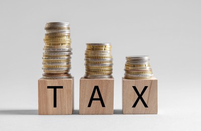 Word Tax made of wooden cubes and coins on white background, space for text