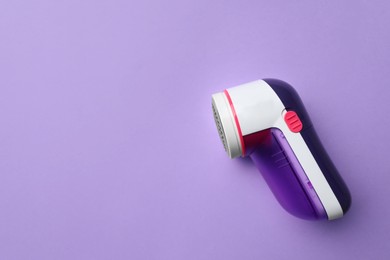 Photo of Modern fabric shaver to remove lint on purple background, top view. Space for text
