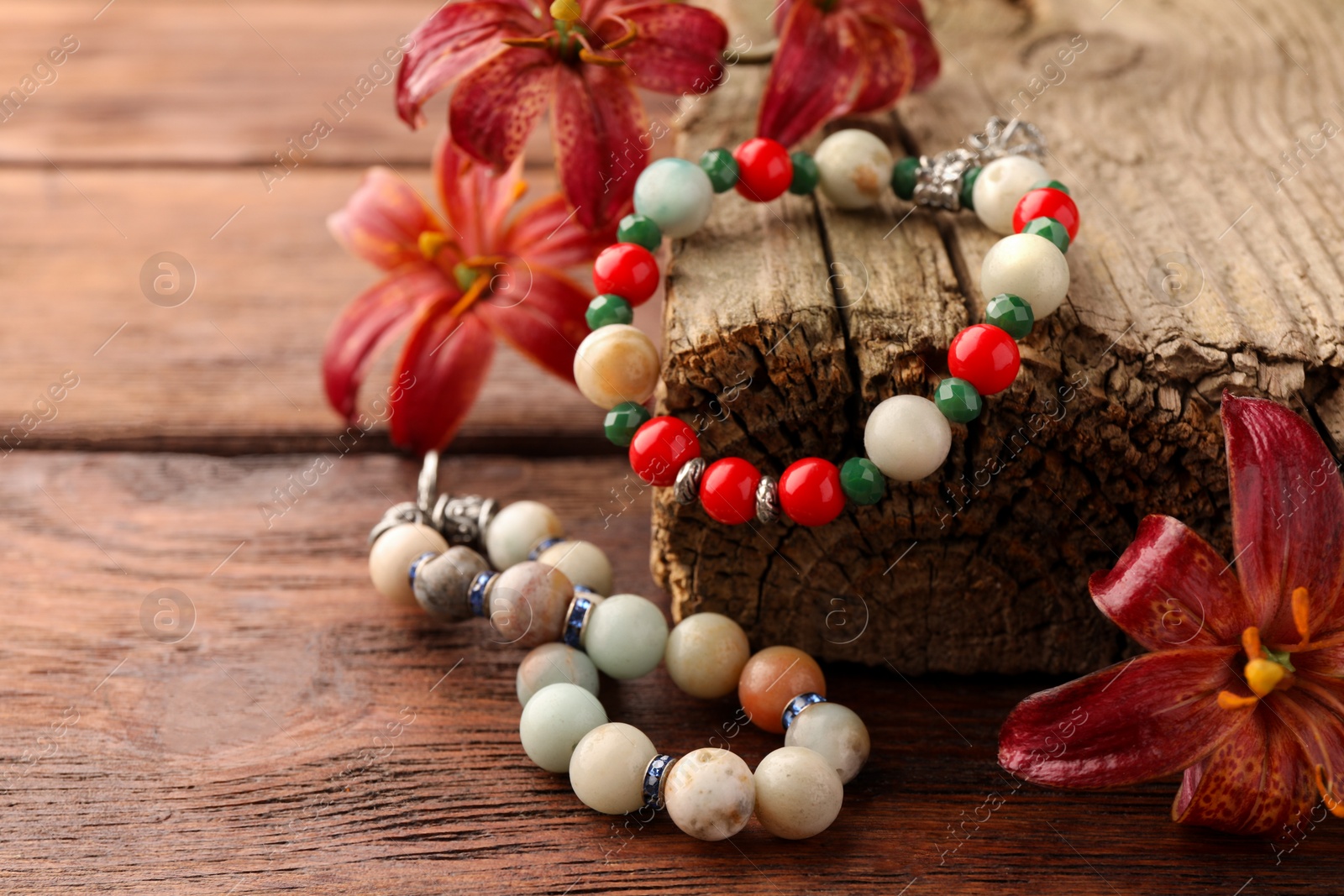 Photo of Stylish presentation of beautiful bracelets with gemstones on wooden table, space for text