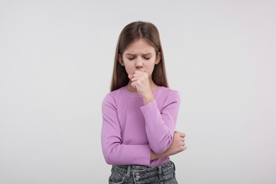 Photo of Sick girl coughing on light background. Cold symptoms