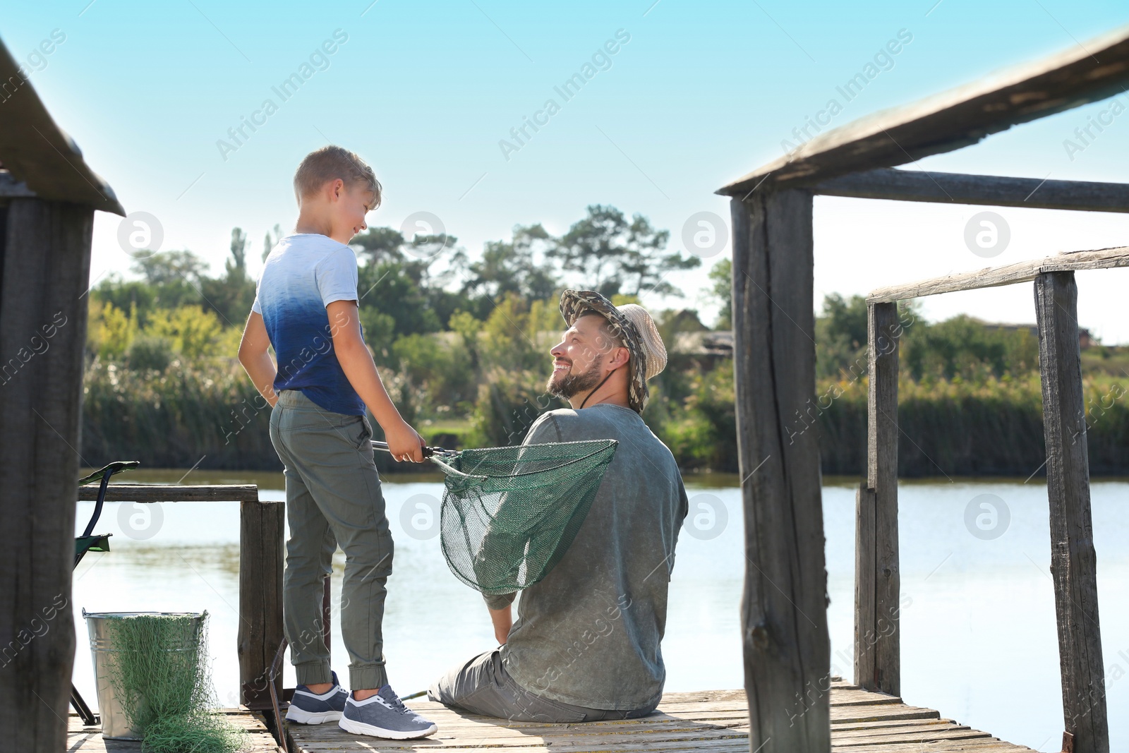 Photo of Father and son fishing together on sunny day