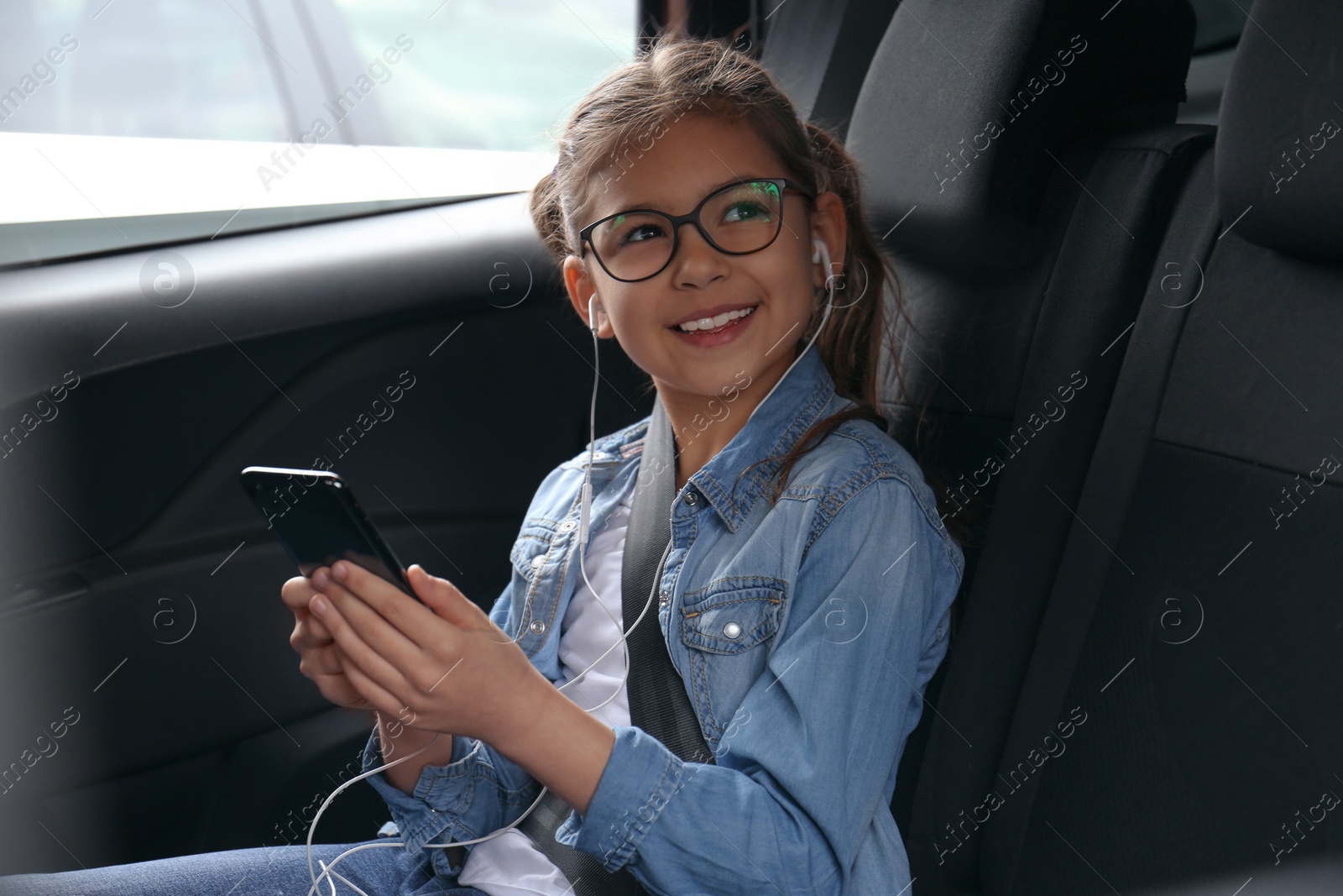 Photo of Cute little girl listening to audiobook in car