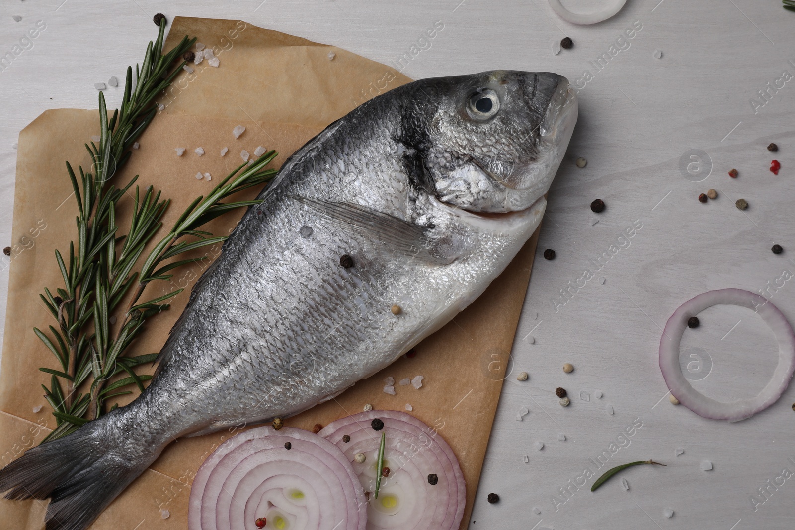 Photo of Raw dorado fish, spices and onion on white wooden table, flat lay