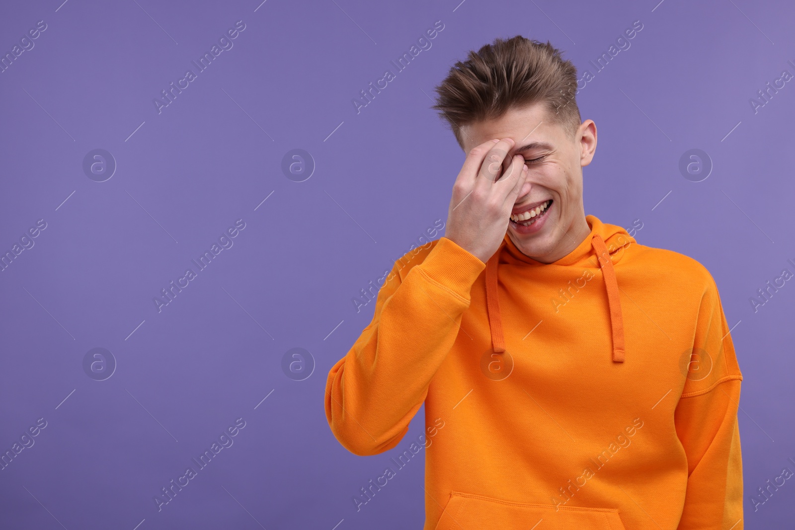 Photo of Young man laughing on violet background. Space for text