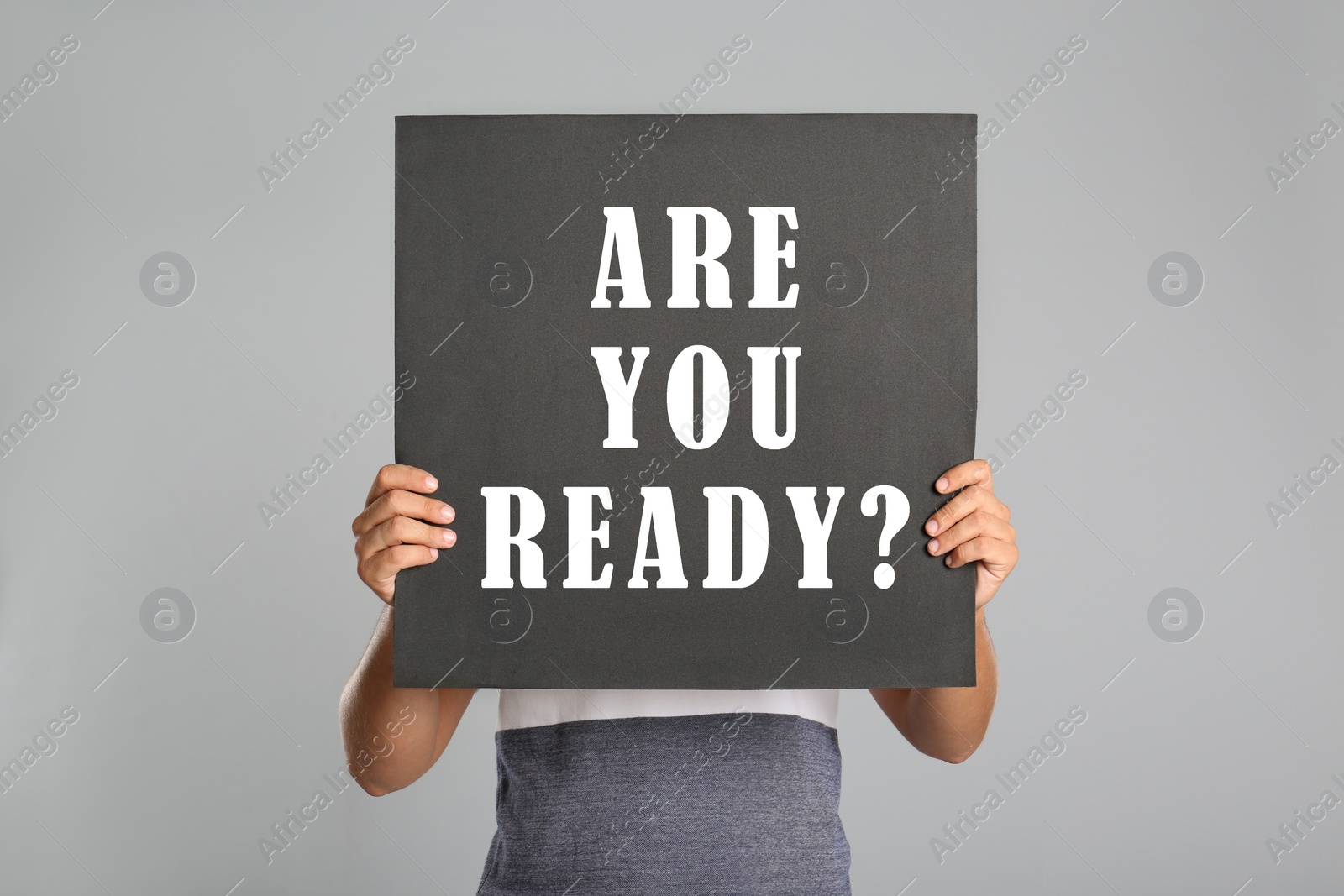 Image of Man holding poster with text Are You Ready? on light grey background