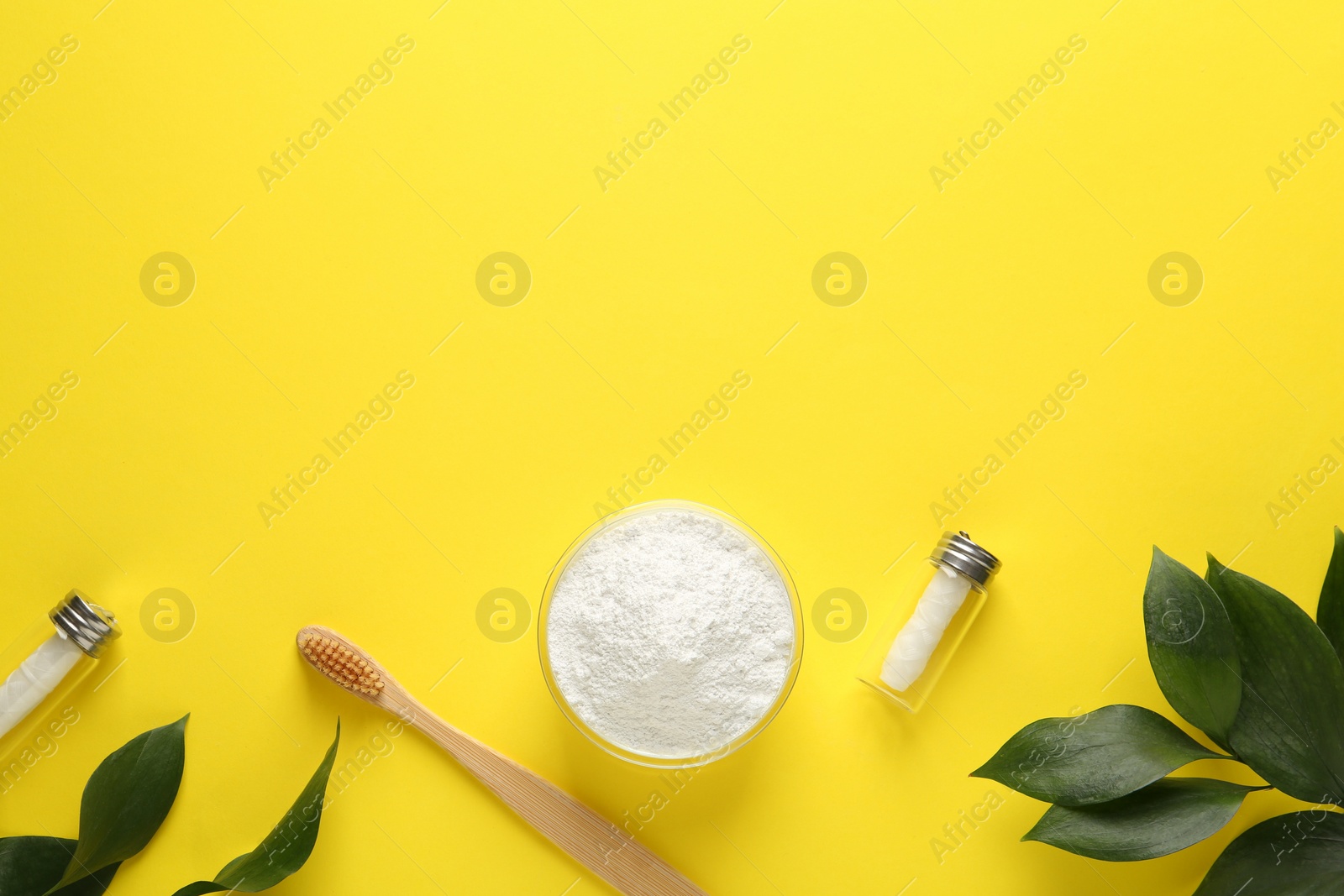 Photo of Bowl of tooth powder, brush dental flosses and plant on yellow background, flat lay. Space for text