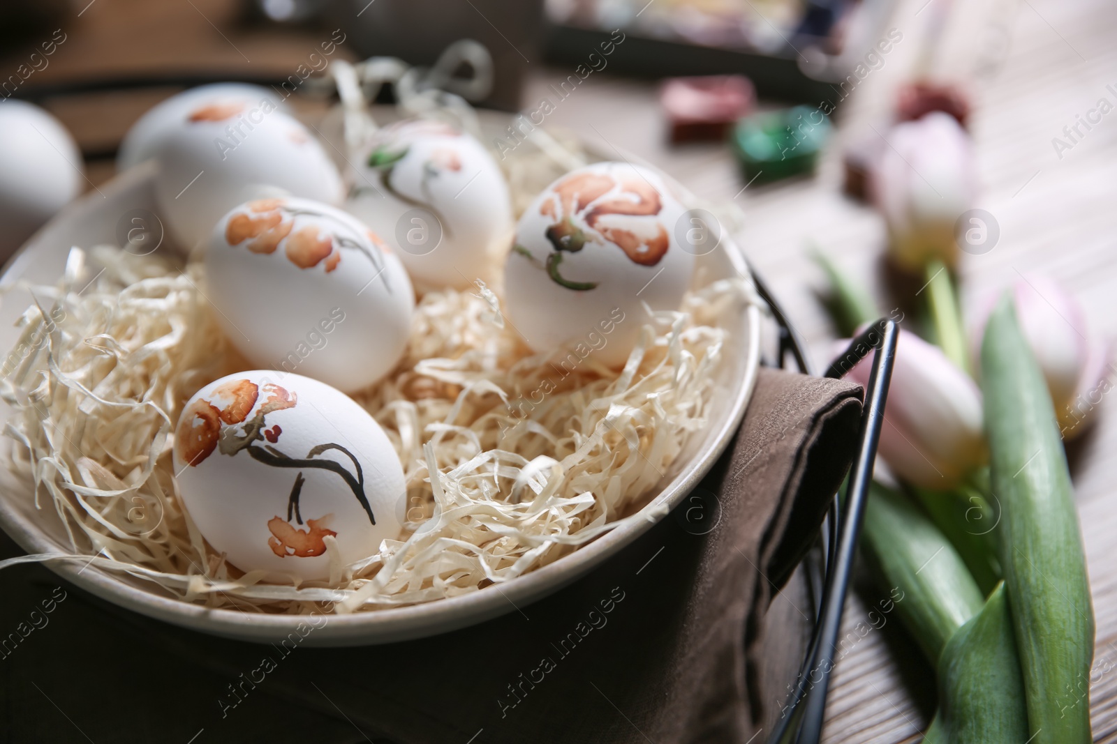 Photo of Beautifully painted Easter eggs in bowl on table, closeup. Space for text