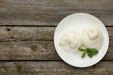 Photo of Delicious burrata cheese with basil on wooden table, top view. Space for text