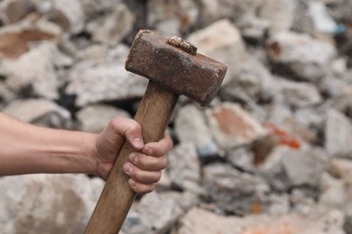 Man with sledgehammer near pile of stones outdoors, closeup. Space for text