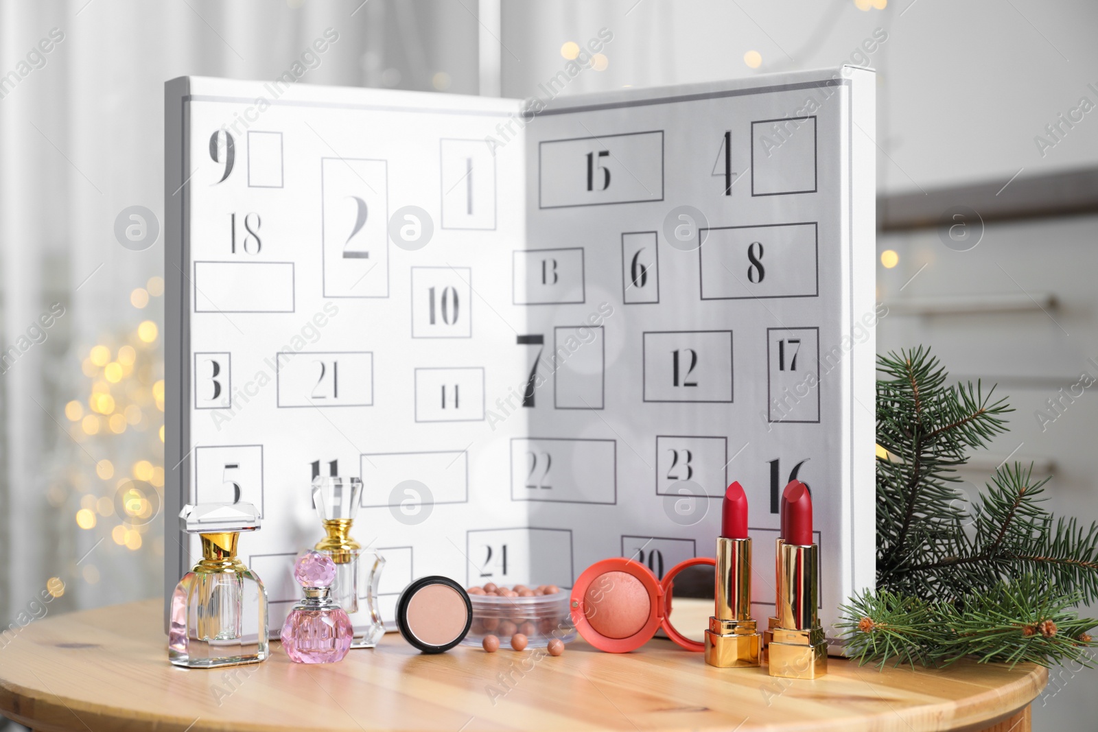 Advent calendar with different cosmetics and perfumes on wooden table against blurred lights. Presents for Christmas Photo of Advent calendar with different cosmetics and perfumes on wooden table against blurred lights. Presents for Christmas