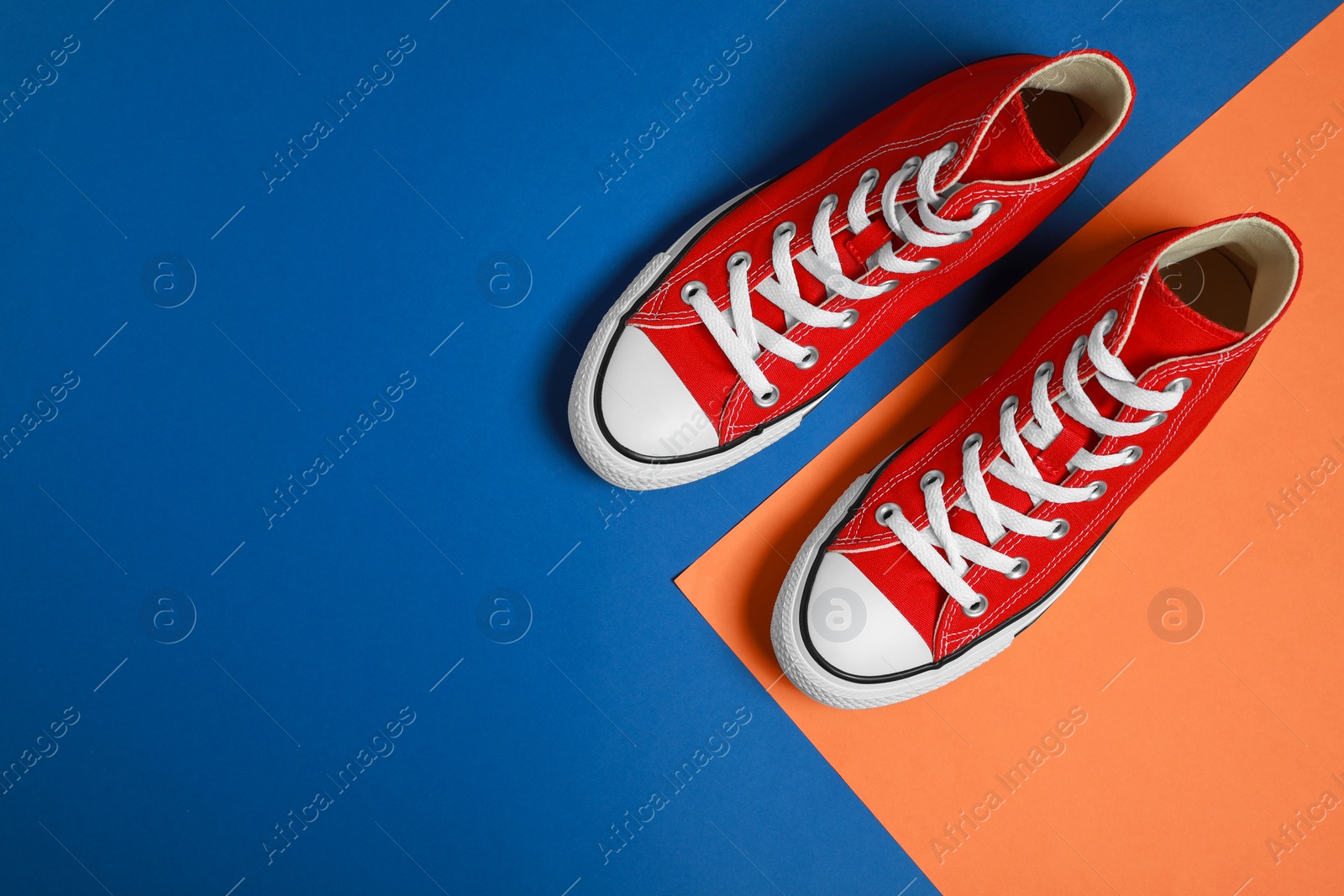 Photo of Pair of new stylish red sneakers on colorful background, flat lay. Space for text