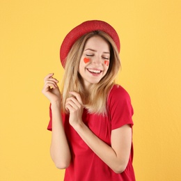 Portrait of woman with heart shaped stickers on face against color background
