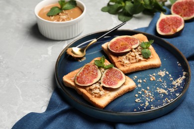 Photo of Tasty toasts served with fig, peanut butter and walnuts on light grey marble table