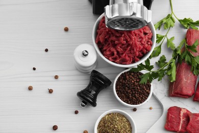 Meat grinder, beef, parsley and spices on white wooden table, flat lay. Space for text