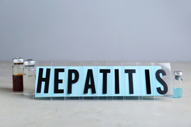 Photo of Word Hepatitis and vials on light grey table