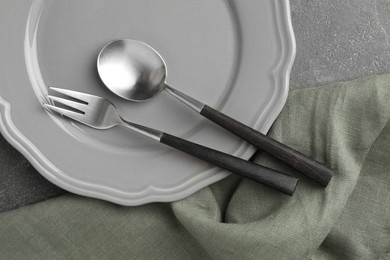 Stylish setting with cutlery, napkin and plate on grey textured table, top view