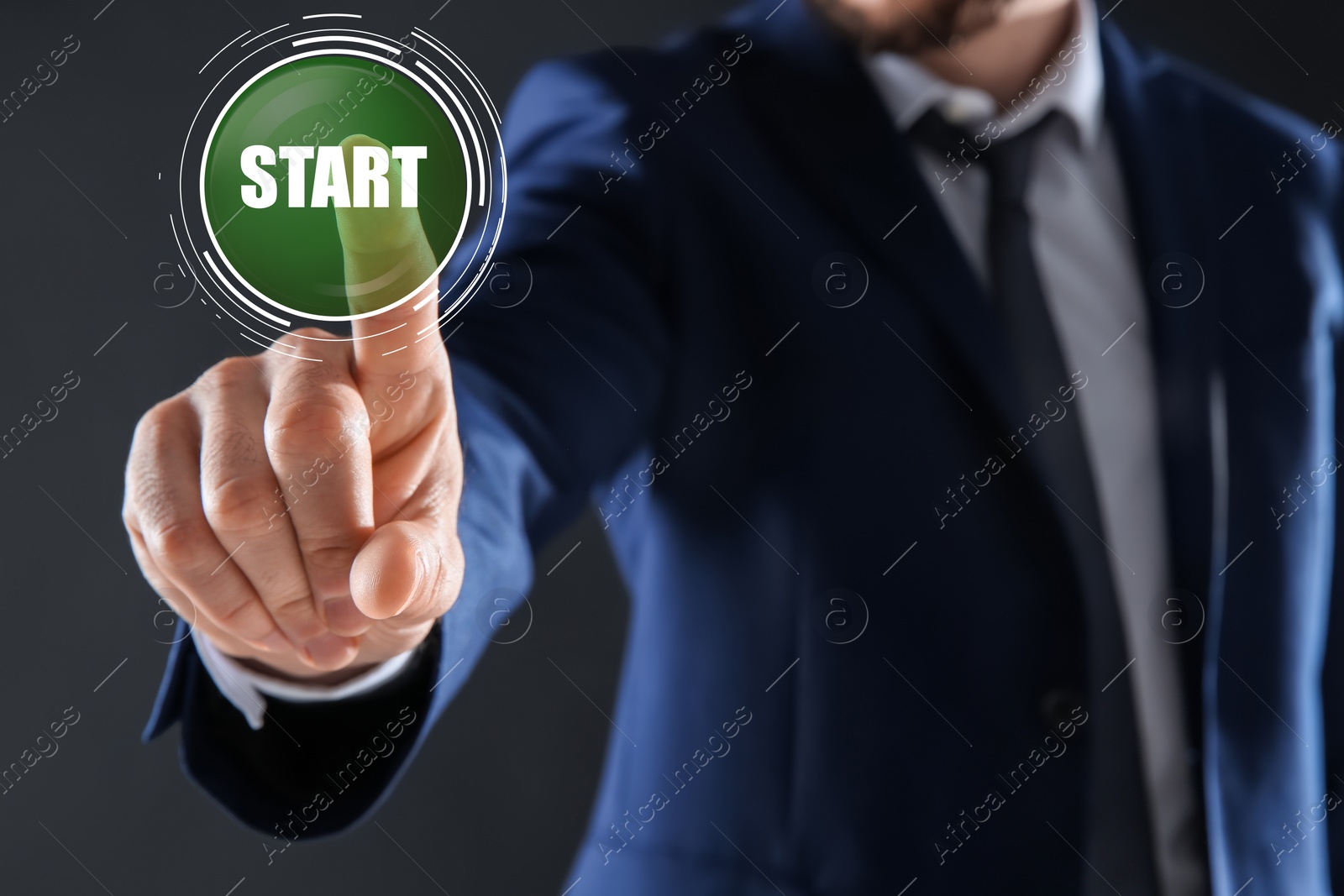 Image of Man pointing at start icon on dark background, closeup