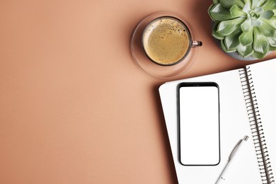 Photo of Modern phone with notebook, cup of coffee and houseplant on coral table, flat lay. Space for text
