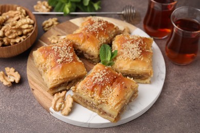 Photo of Eastern sweets. Pieces of tasty baklava and tea on brown table, closeup